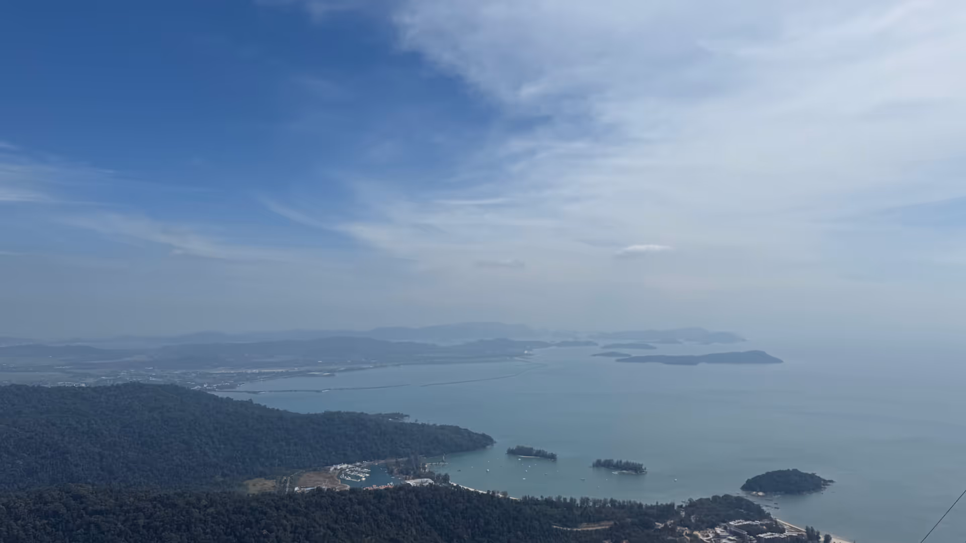 Looking down at the islands and the hazy blue ocean from a high mountain viewpoint.
