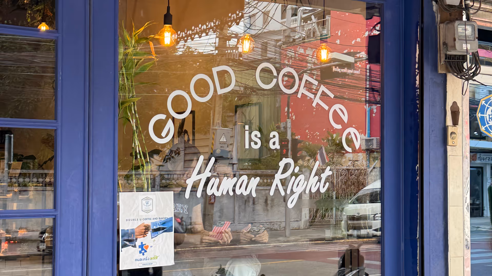 A blue coffee shop window with "GOOD COFFEE is a Human Right" written in white.