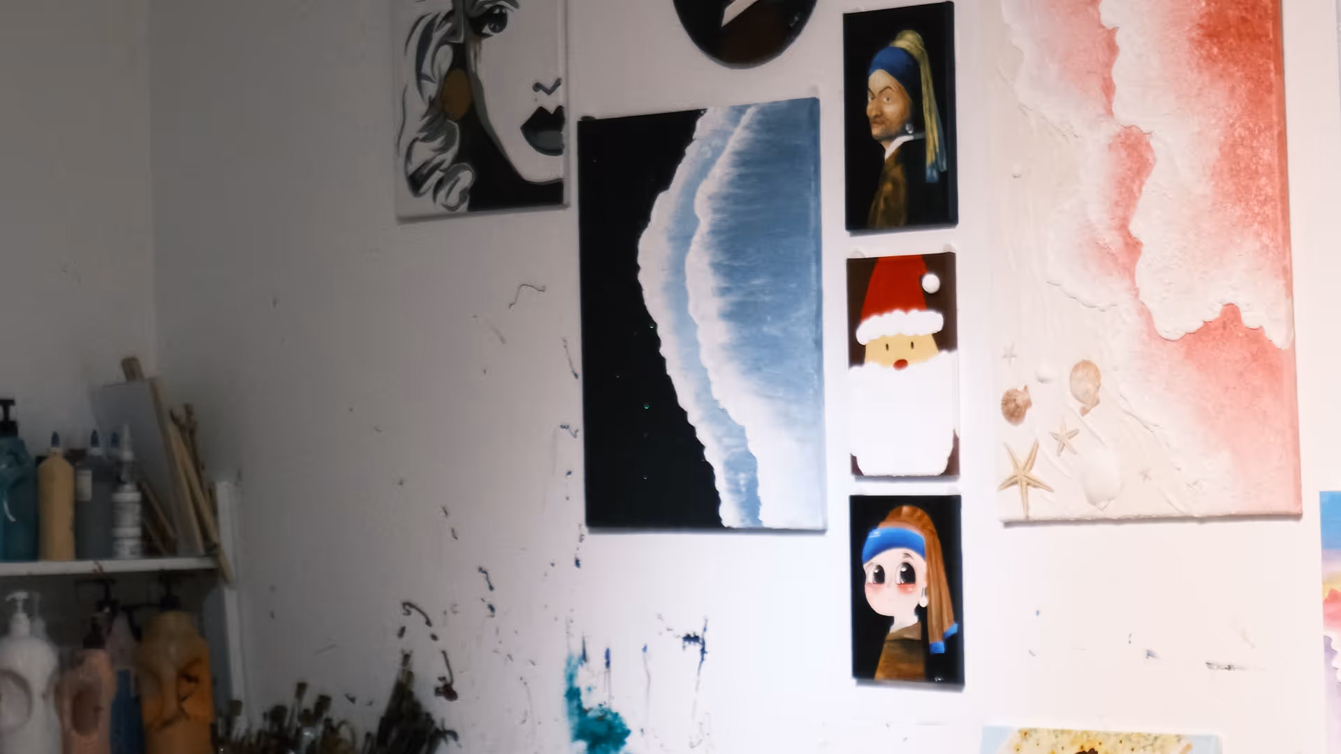 An artist's studio wall covered in paintings and sketches, shot at a tilted angle with a paint-splattered ladder in the corner.