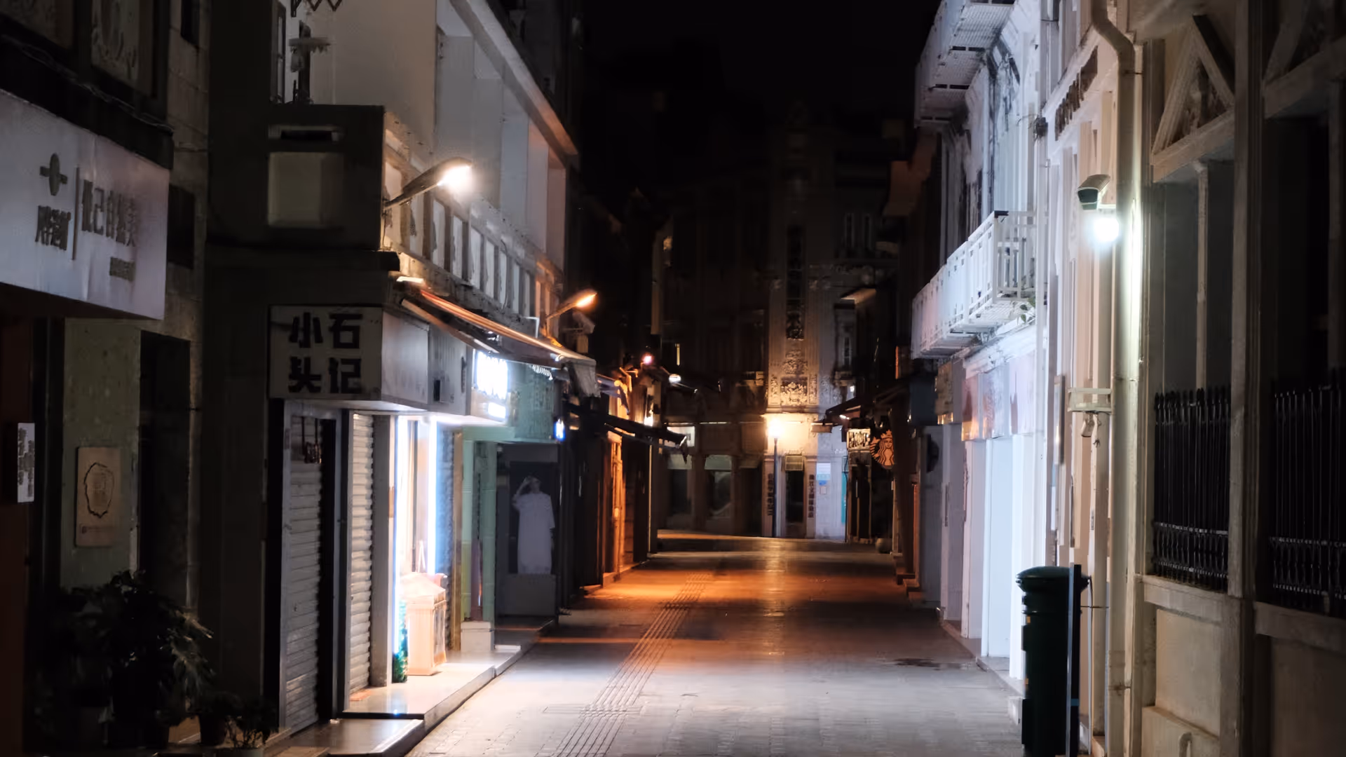 A long narrow alley on Gulangyu at night, lit by warm lamplight fading into darkness.