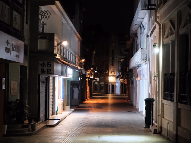 A long narrow alley on Gulangyu at night, lit by warm lamplight fading into darkness.