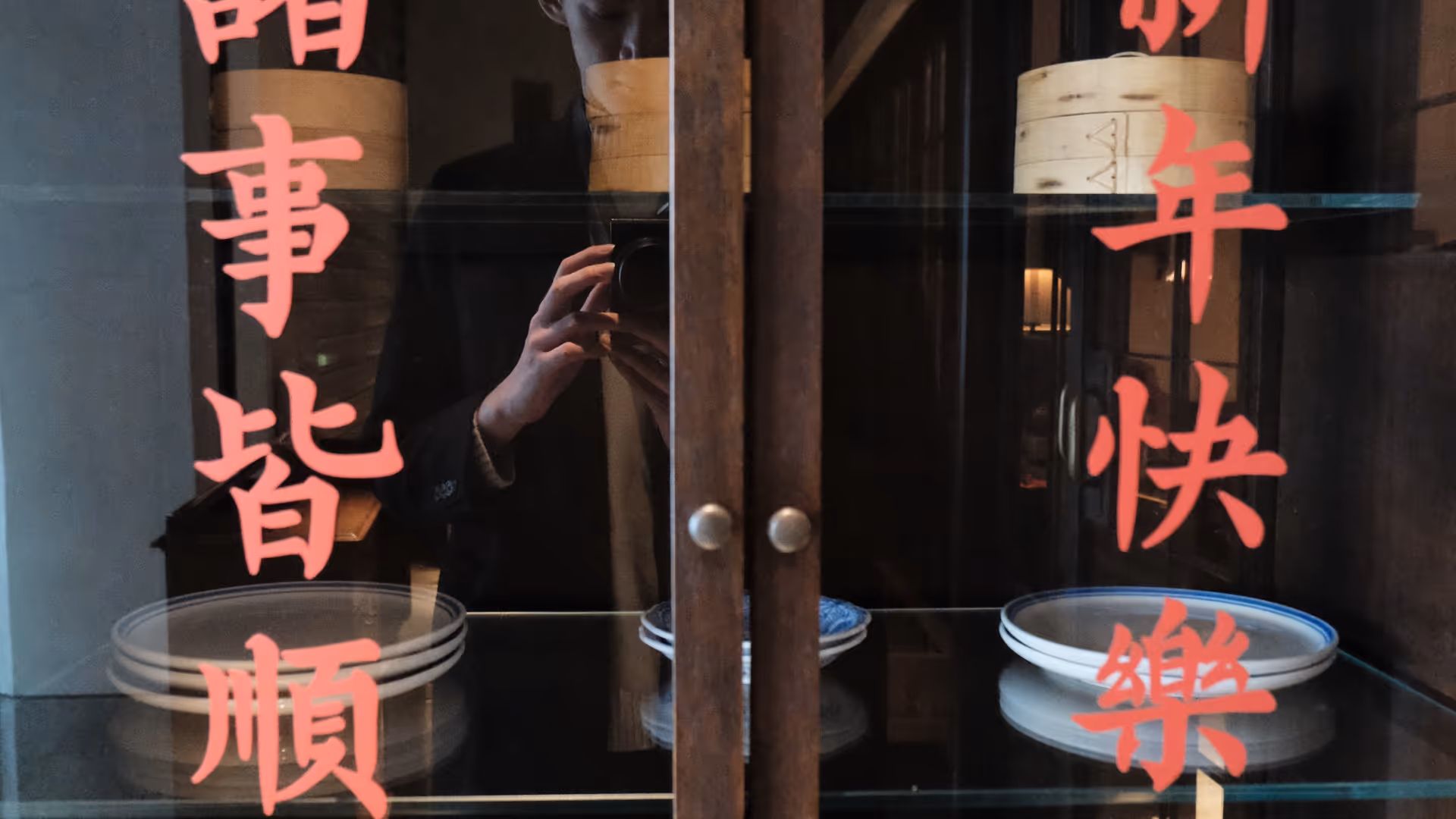 A wooden glass cabinet with red Chinese calligraphy and blue-and-white porcelain bowls inside a Gulangyu restaurant.