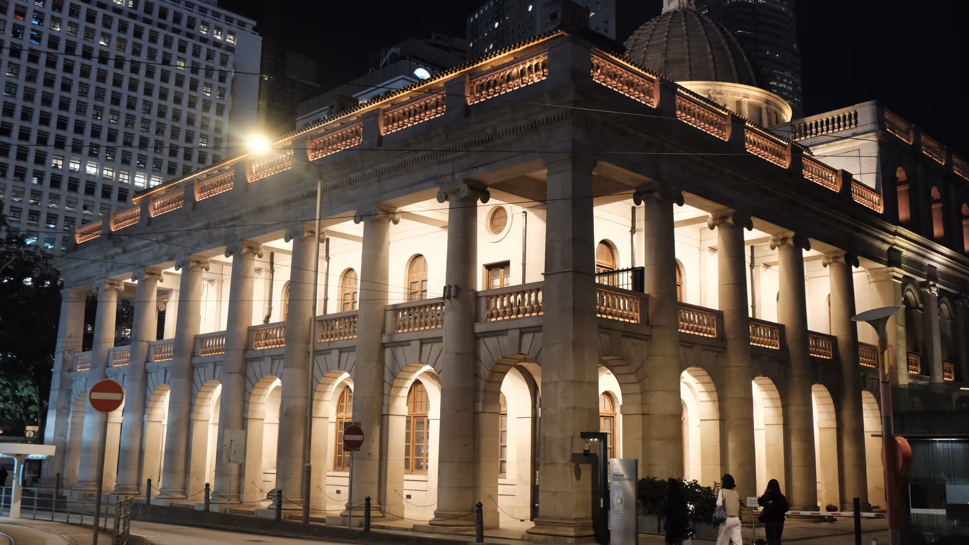 The Court of Final Appeal building in Central lit up at night, its neoclassical columns glowing against the surrounding glass towers.