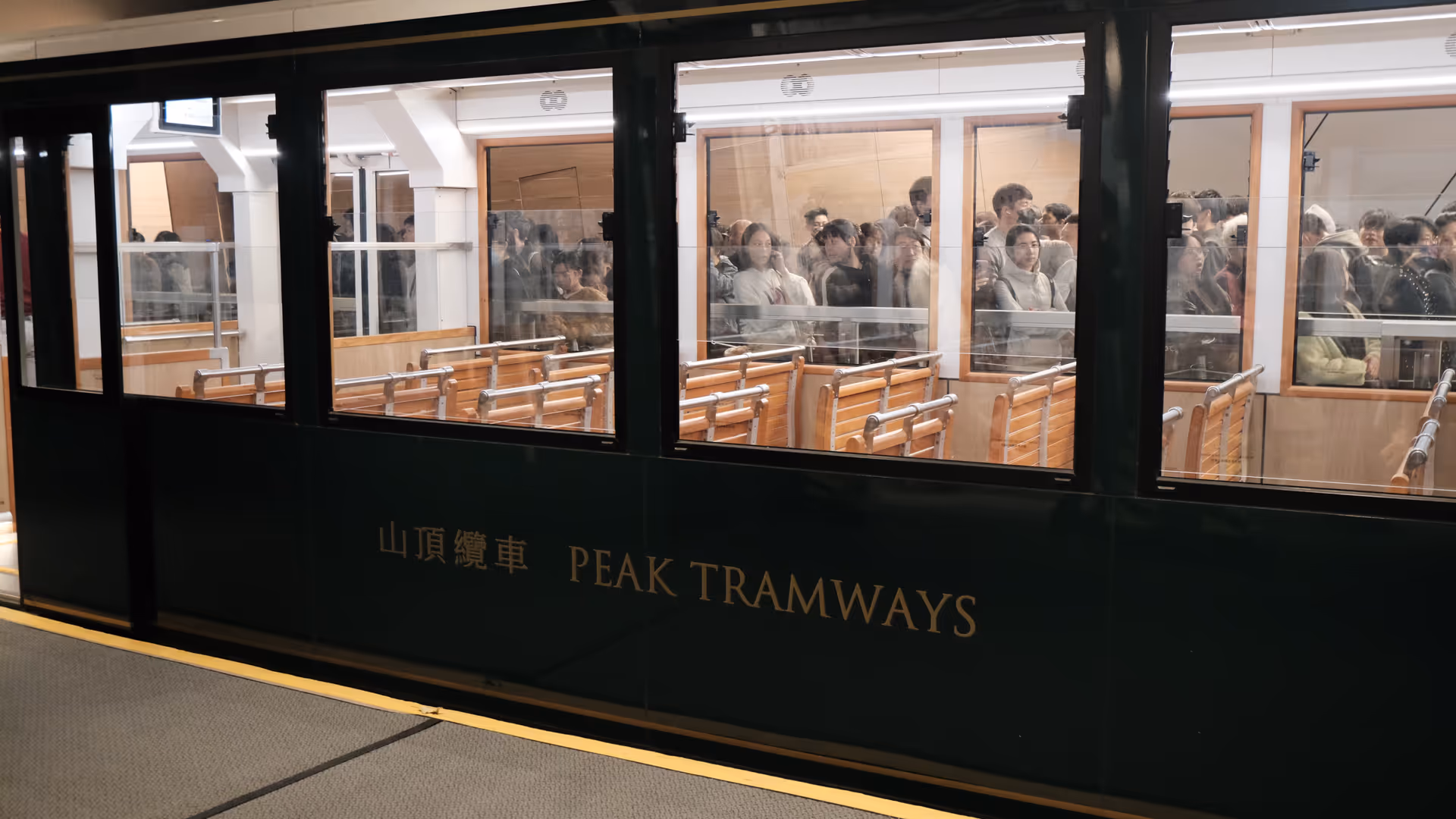 The dark green Peak Tram carriage at the station, packed with passengers heading back down.