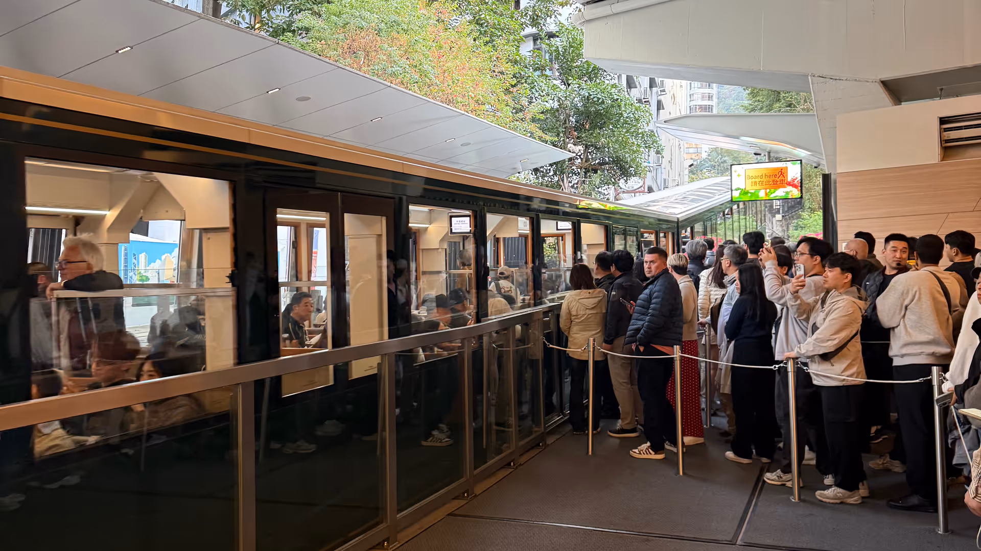 A long queue of visitors waiting to board the Peak Tram inside the lower terminus.