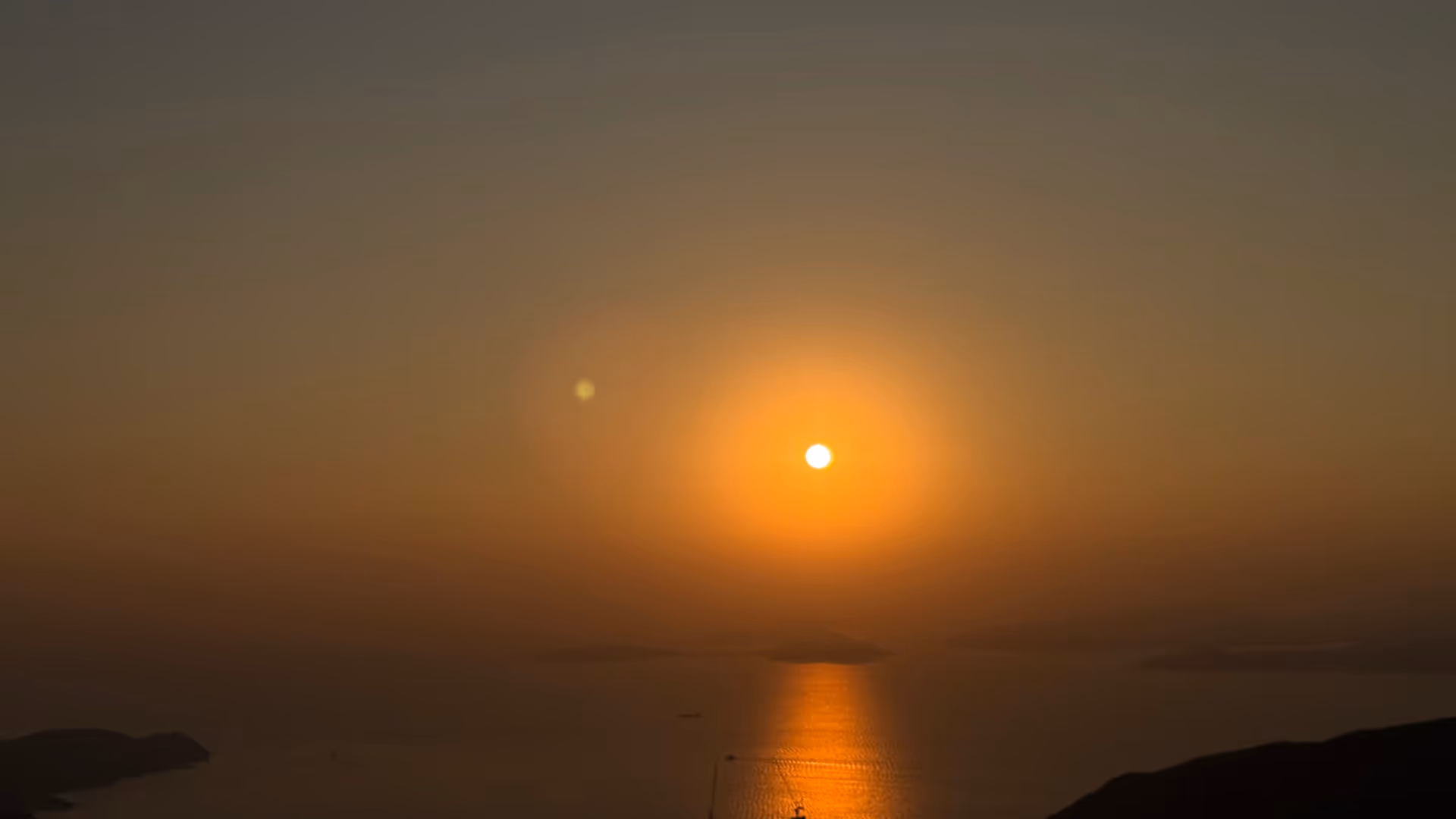 A deep orange sunset over the South China Sea seen from Victoria Peak, the sun sinking behind distant islands.