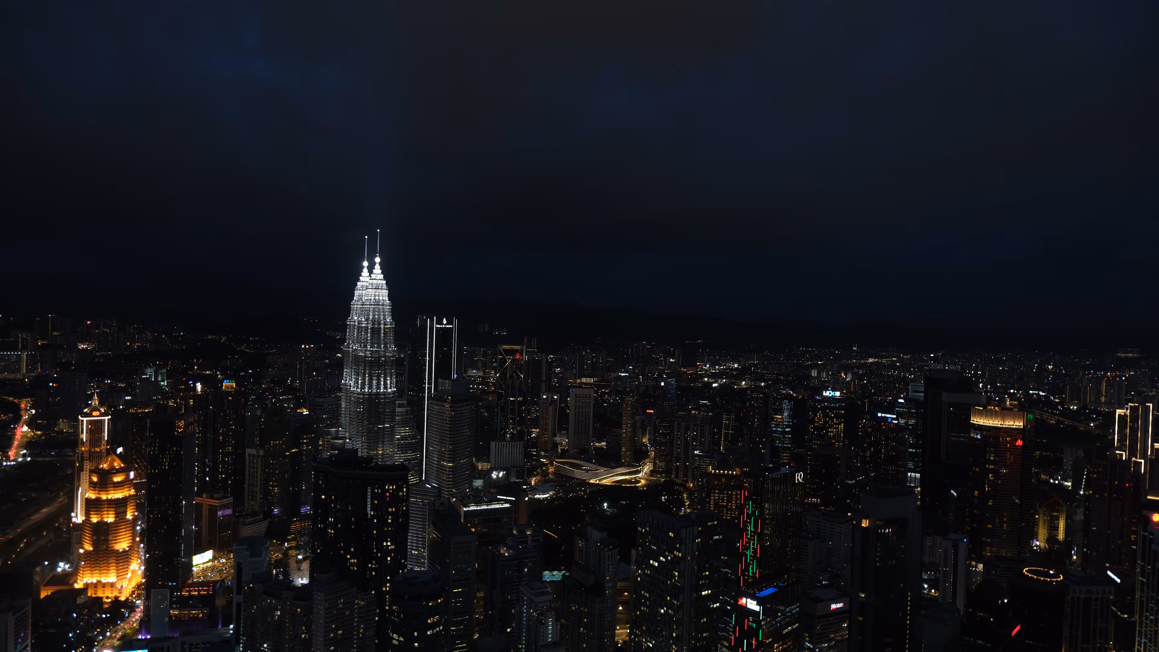 The Petronas Twin Towers lit up against a dark KL skyline, shot from the top of KL Tower.