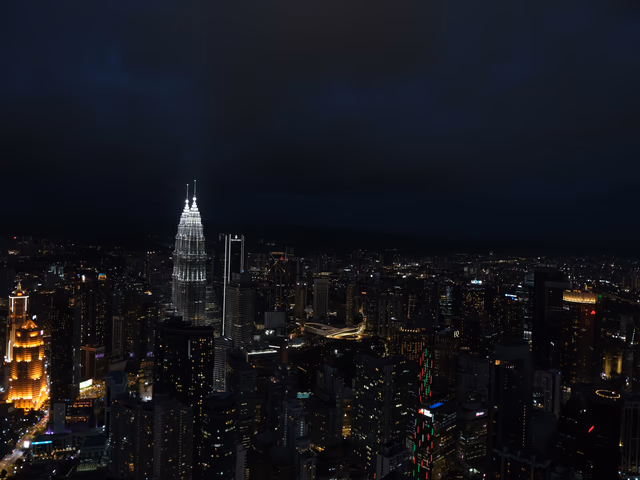 The Petronas Twin Towers lit up against a dark KL skyline, shot from the top of KL Tower.