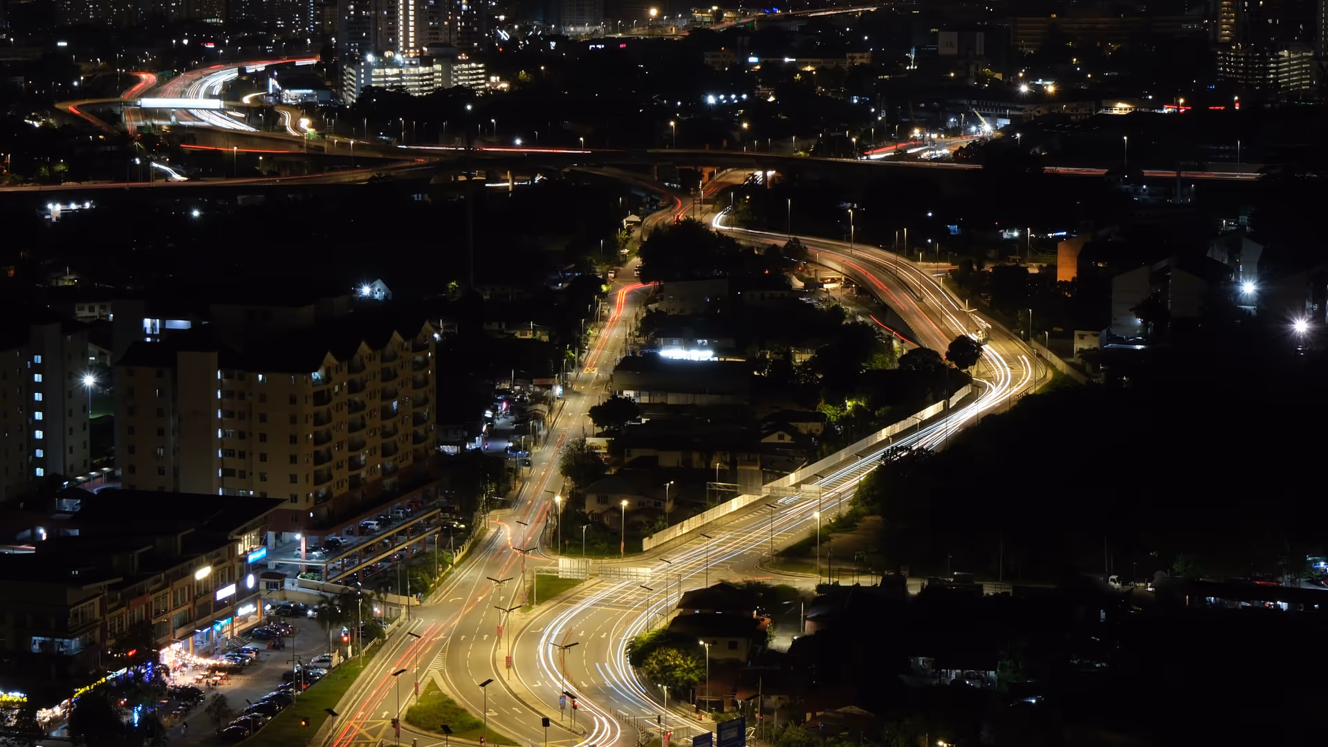 A sweeping aerial view of KL's highway interchange lit up at night, shot from the top of KL Tower.