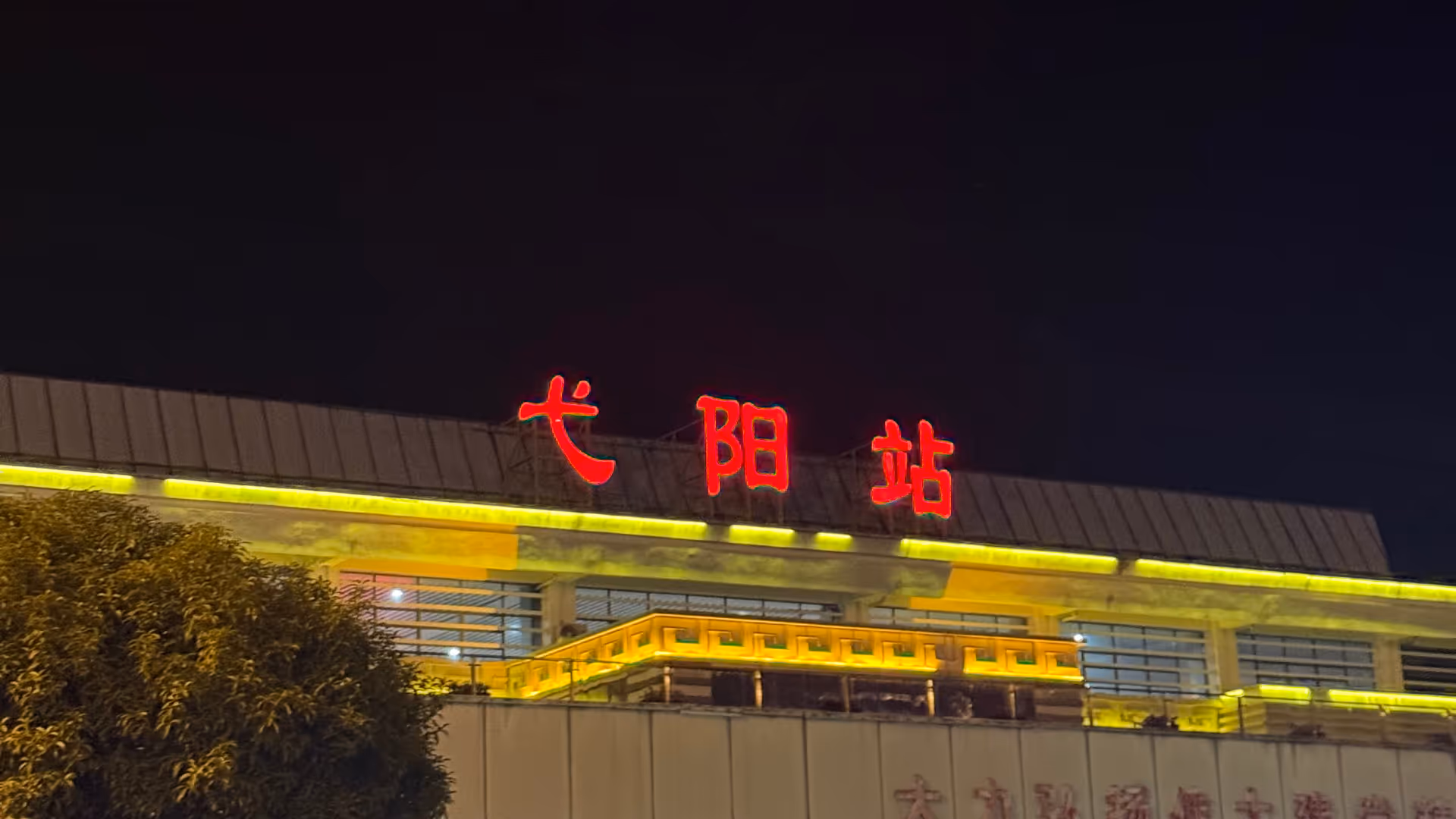 A building in Liyang at night with large red Chinese characters glowing against a dark sky.