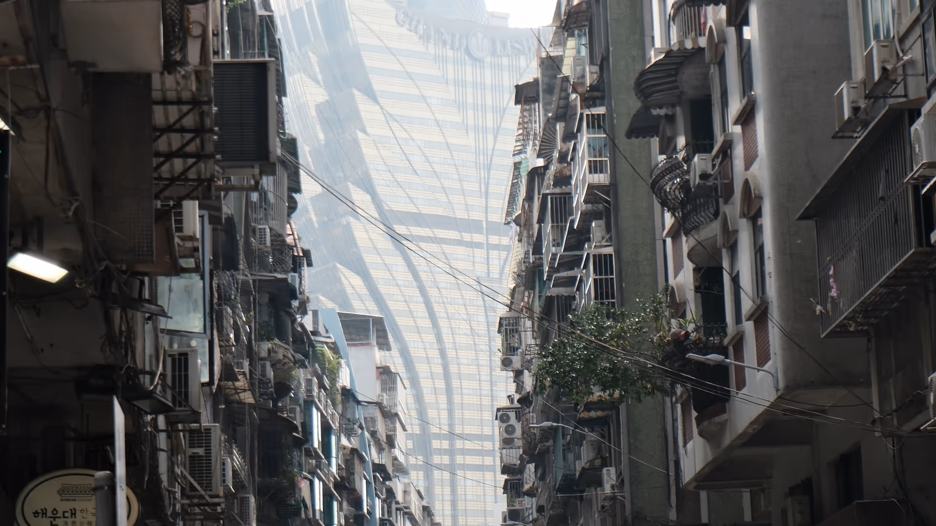 A busy Macao street viewed from above, packed with cars and motorbikes weaving between colonial-era shophouses.