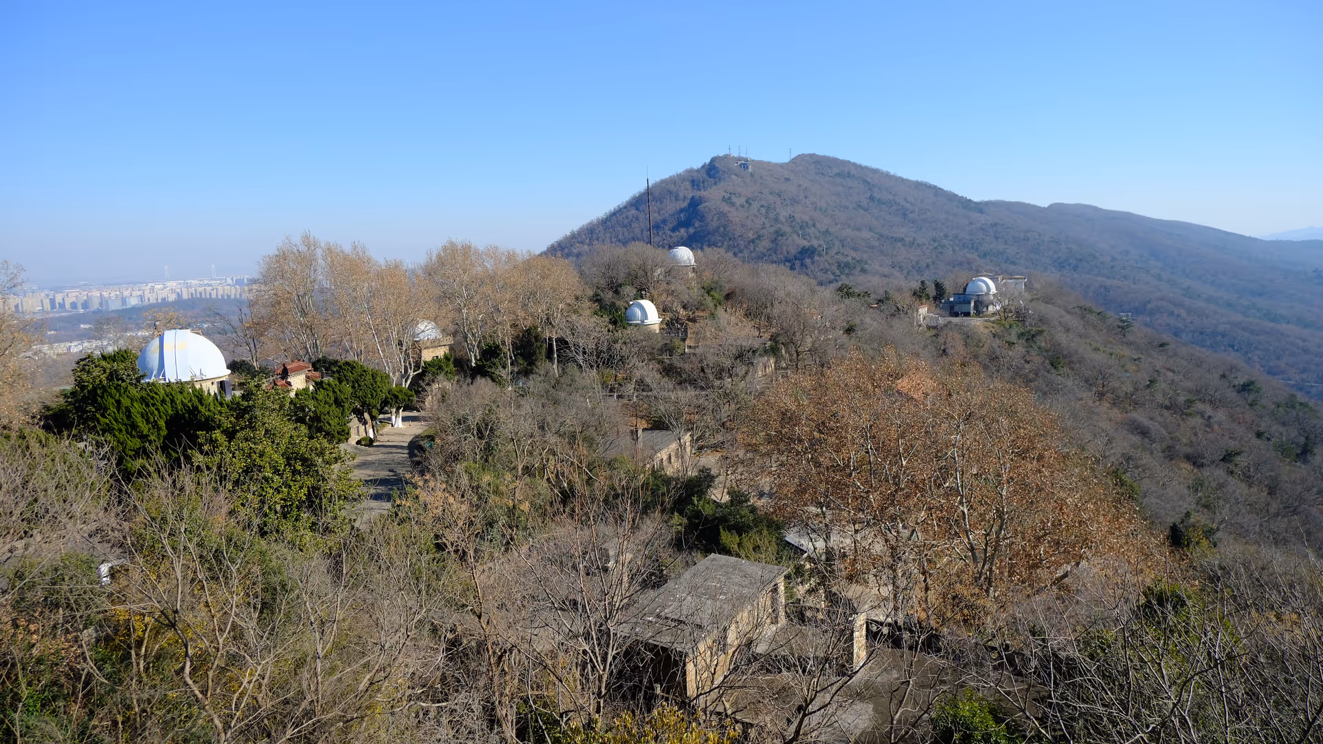The Purple Mountain Observatory domes scattered across a hillside under a clear blue winter sky in Nanjing.