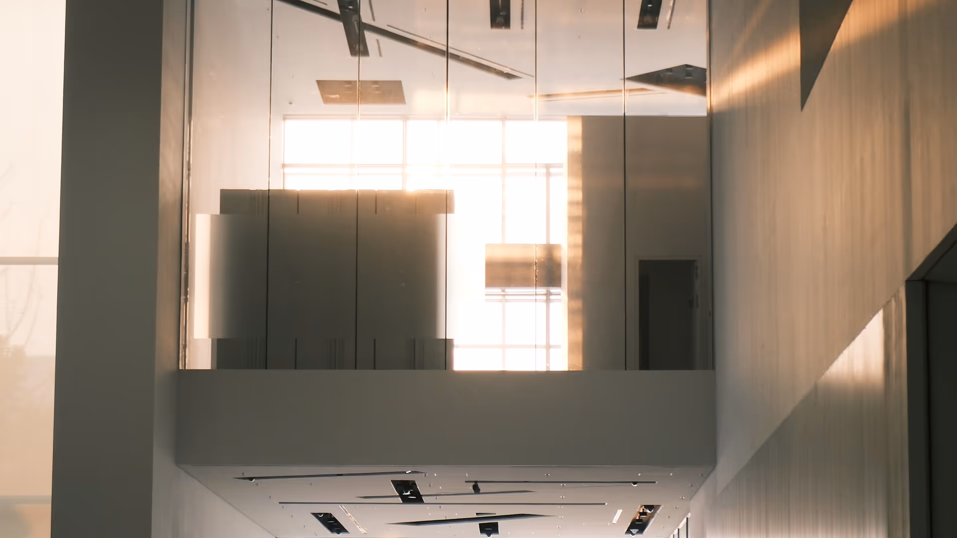The stark white interior of the MAP Museum in Pudong, visitors silhouetted against large backlit windows at the top of the stairs.