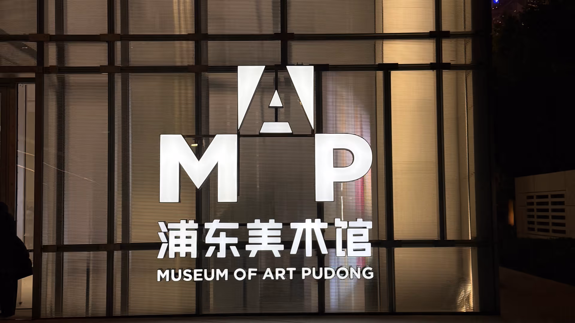 The illuminated MAP Museum of Art Pudong sign glowing white against a dark interior at night.