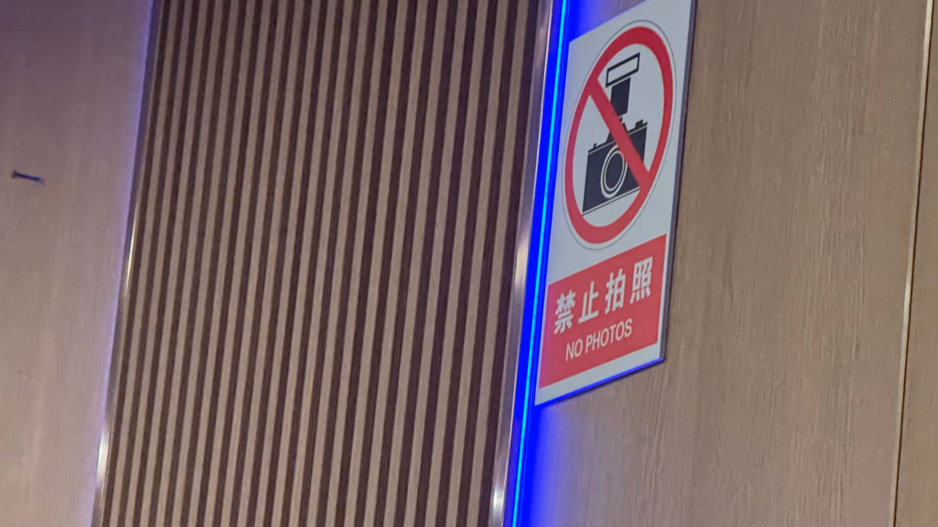 A no-photography sign inside the North Korean restaurant, lit with a blue LED strip above it.
