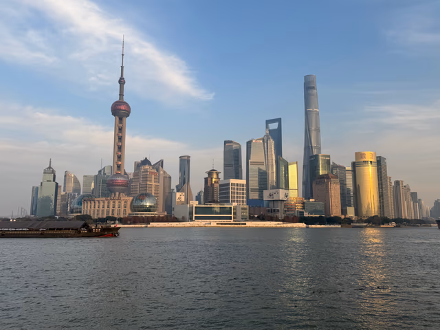 The Pudong skyline across the Huangpu River on a clear winter afternoon, the Oriental Pearl Tower and Shanghai Tower dominating the view.