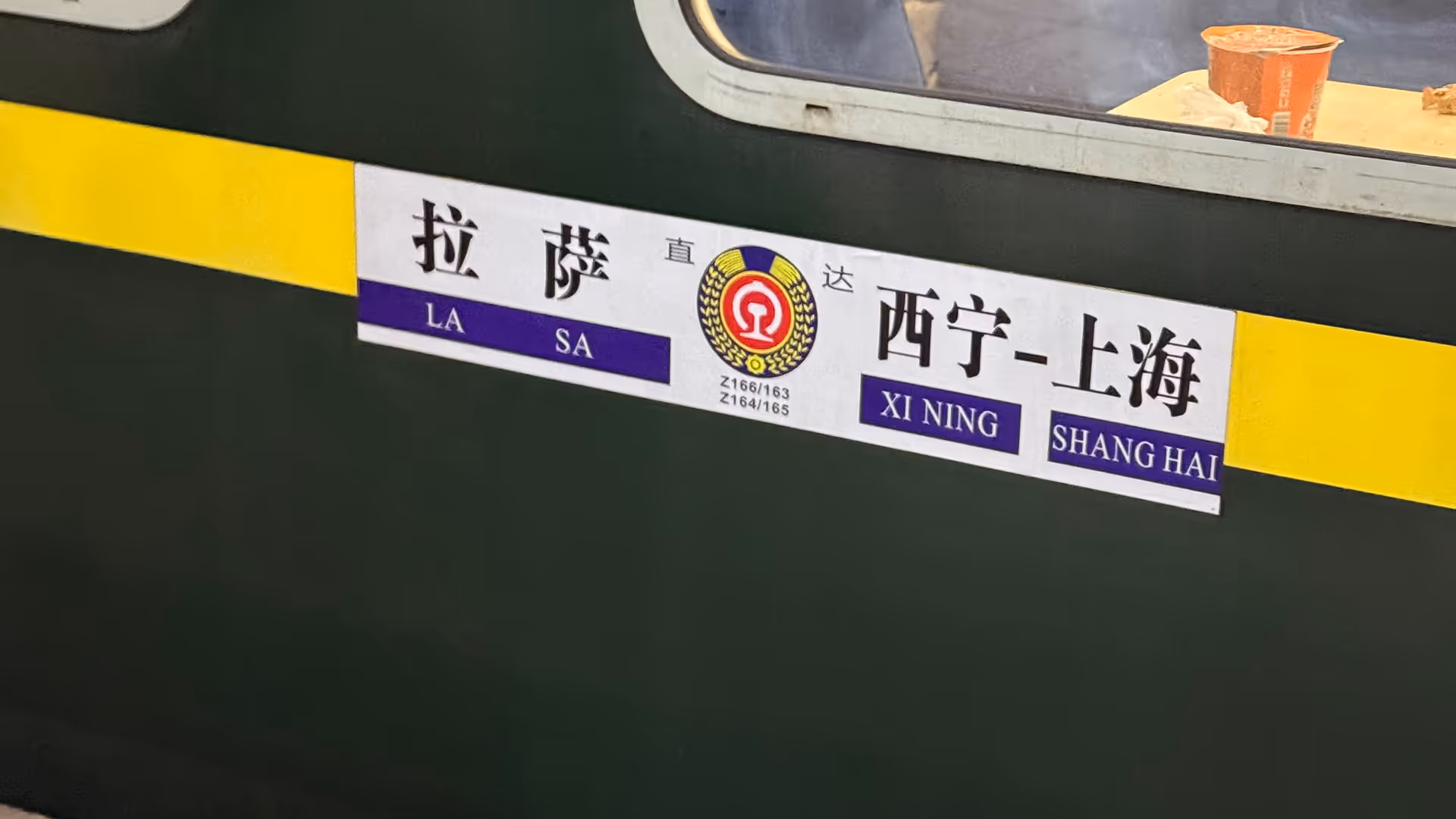 A destination plate on a green Chinese train carriage showing the Lhasa to Shanghai route.