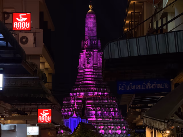 The Wat Arun spire glowing bright purple