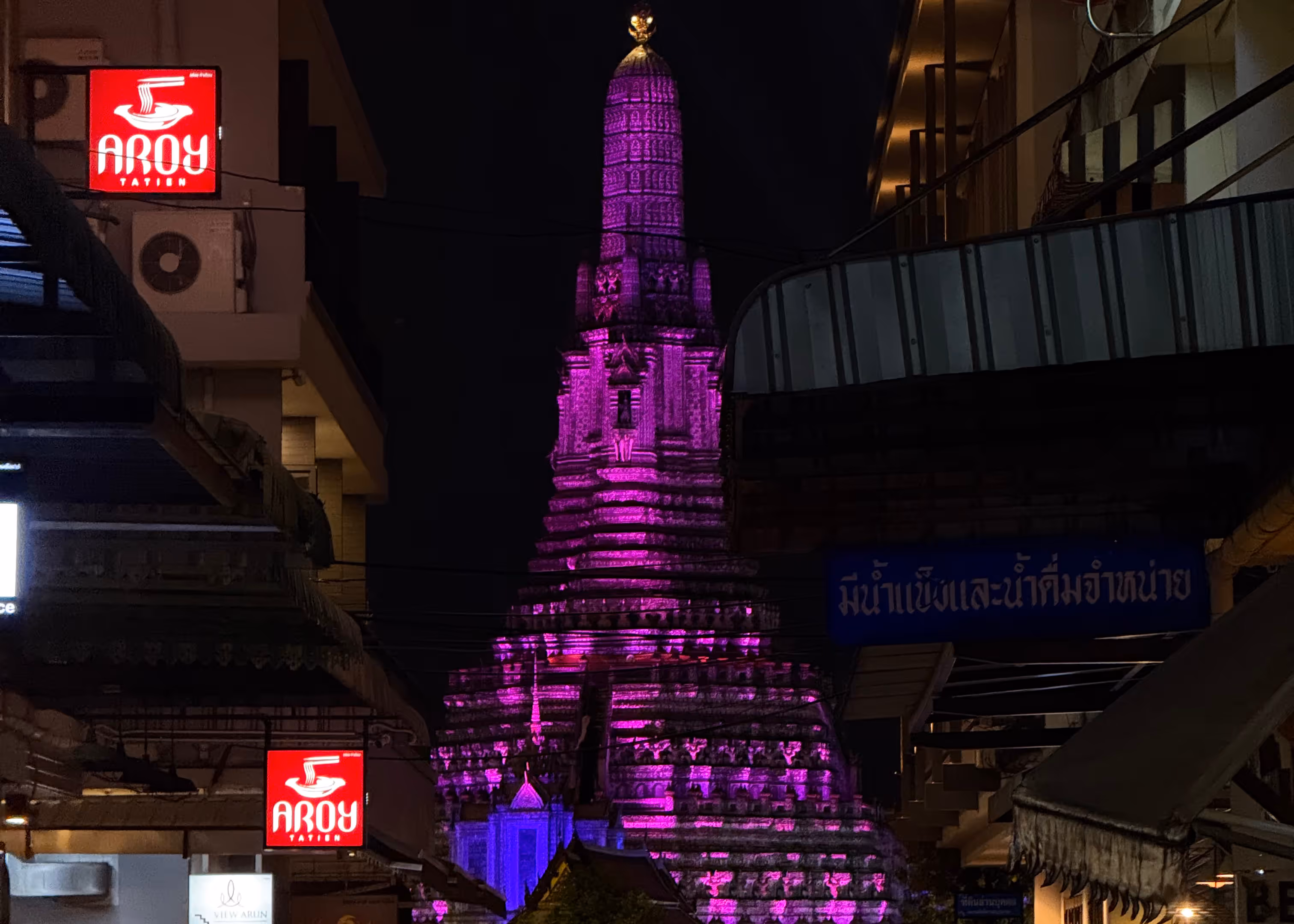 The Wat Arun spire glowing bright purple