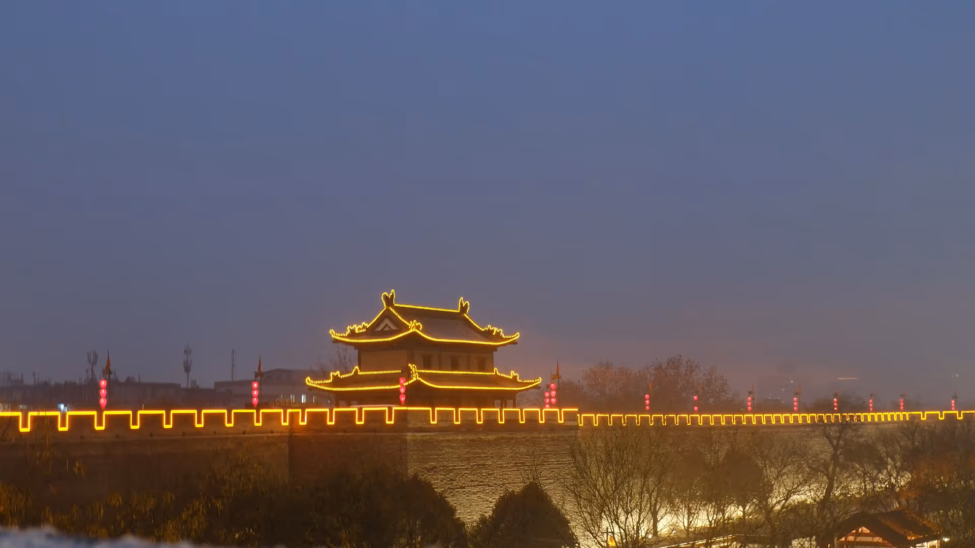 Xi'an's ancient city wall illuminated in warm gold light at dusk, stretching into the distance.