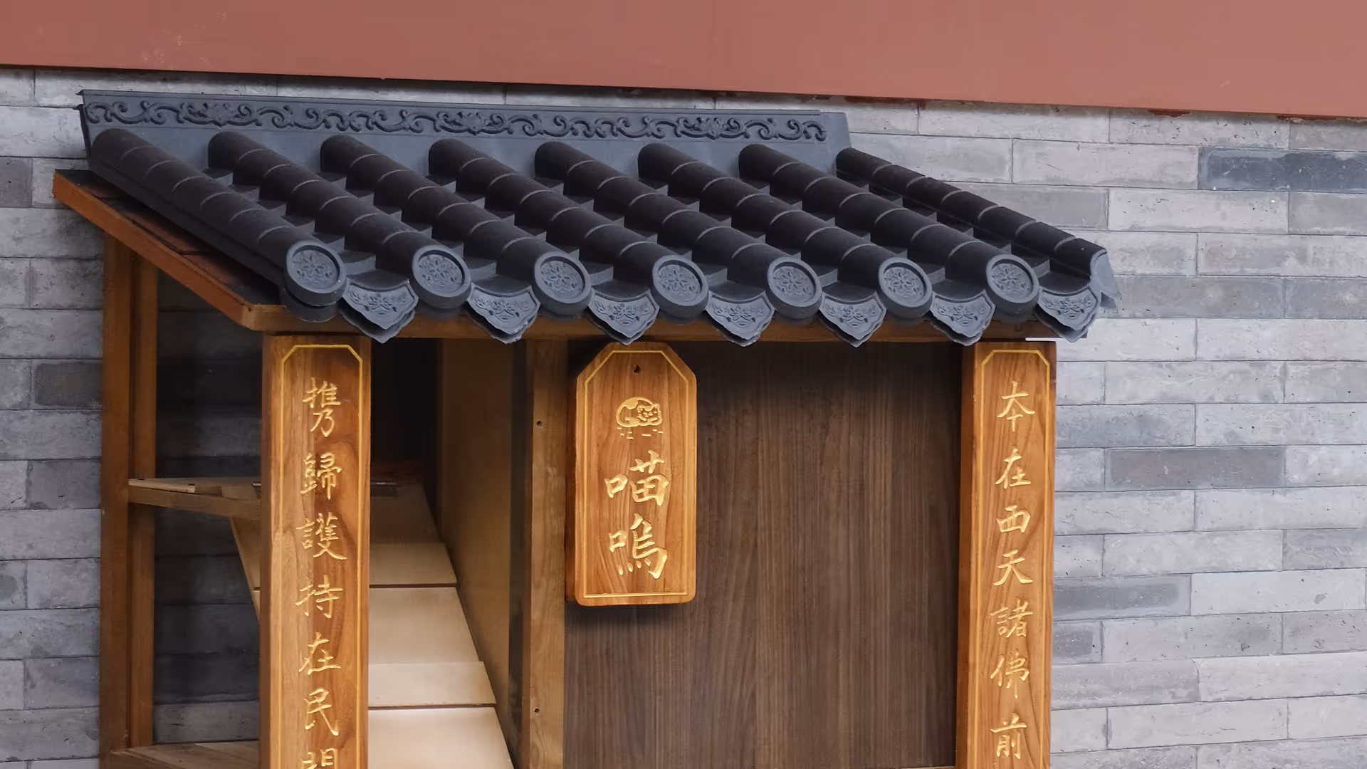 An ornate wooden temple signboard with gold Chinese script, viewed from above with a small potted plant beside it.