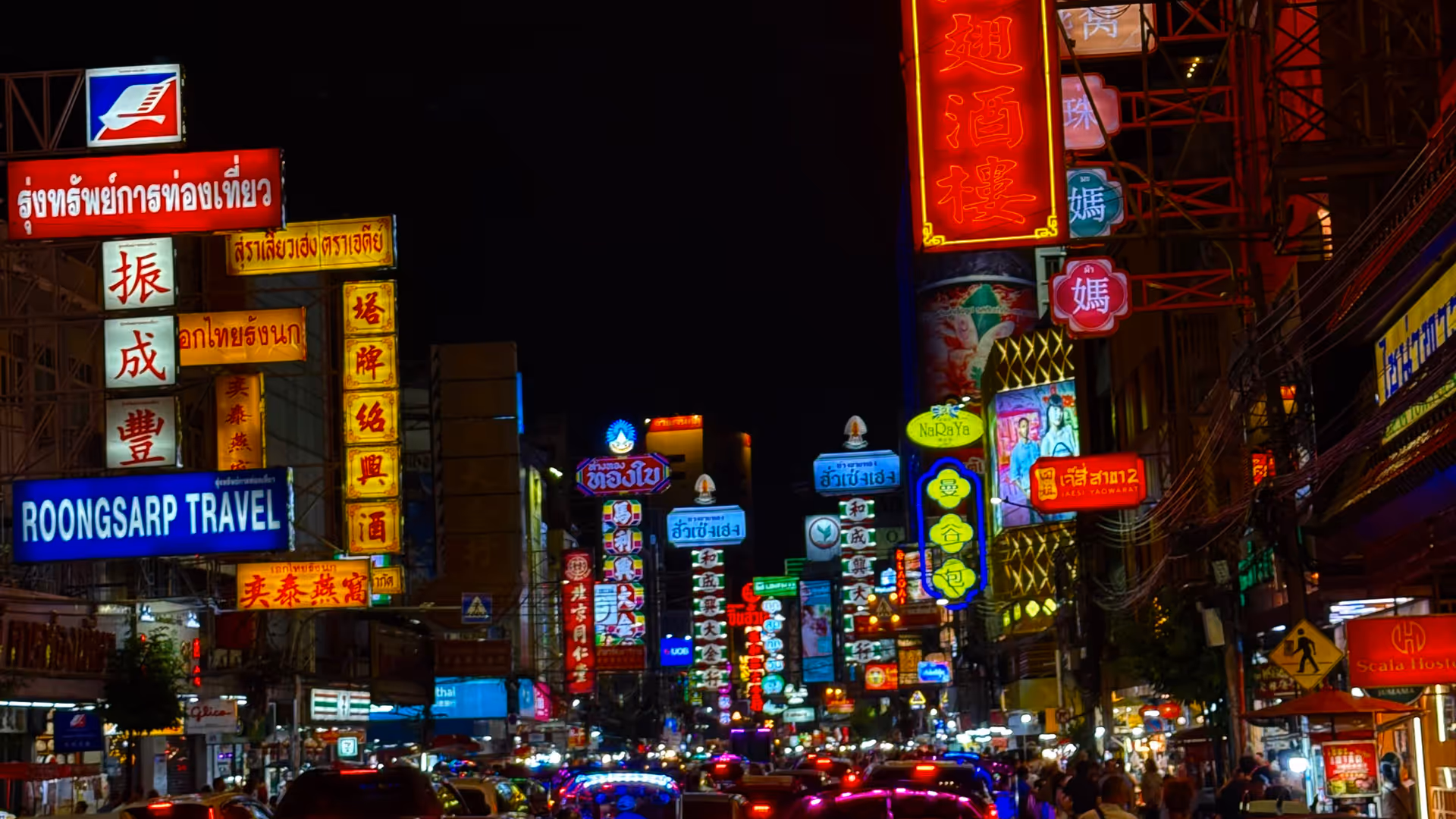 Busy traffic in Chinatown at night, under a dense canopy of red and yellow neon signs.