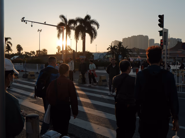 Commuters crossing a zebra crossing at golden hour in Zhuhai, palm trees silhouetted against a warm sunrise sky.